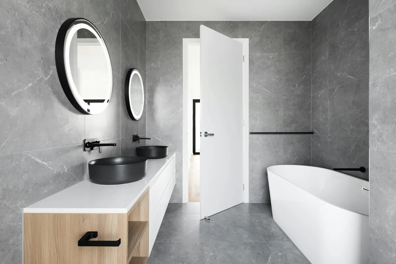 Grey stone bathroom with a freestanding tub and matte black taps