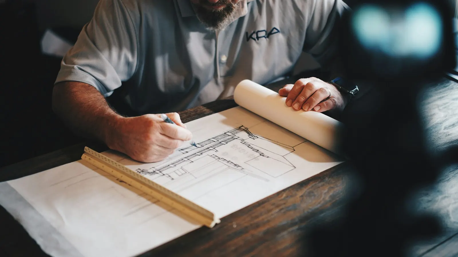 Contractor marking up a floor plan with a pencil and ruler